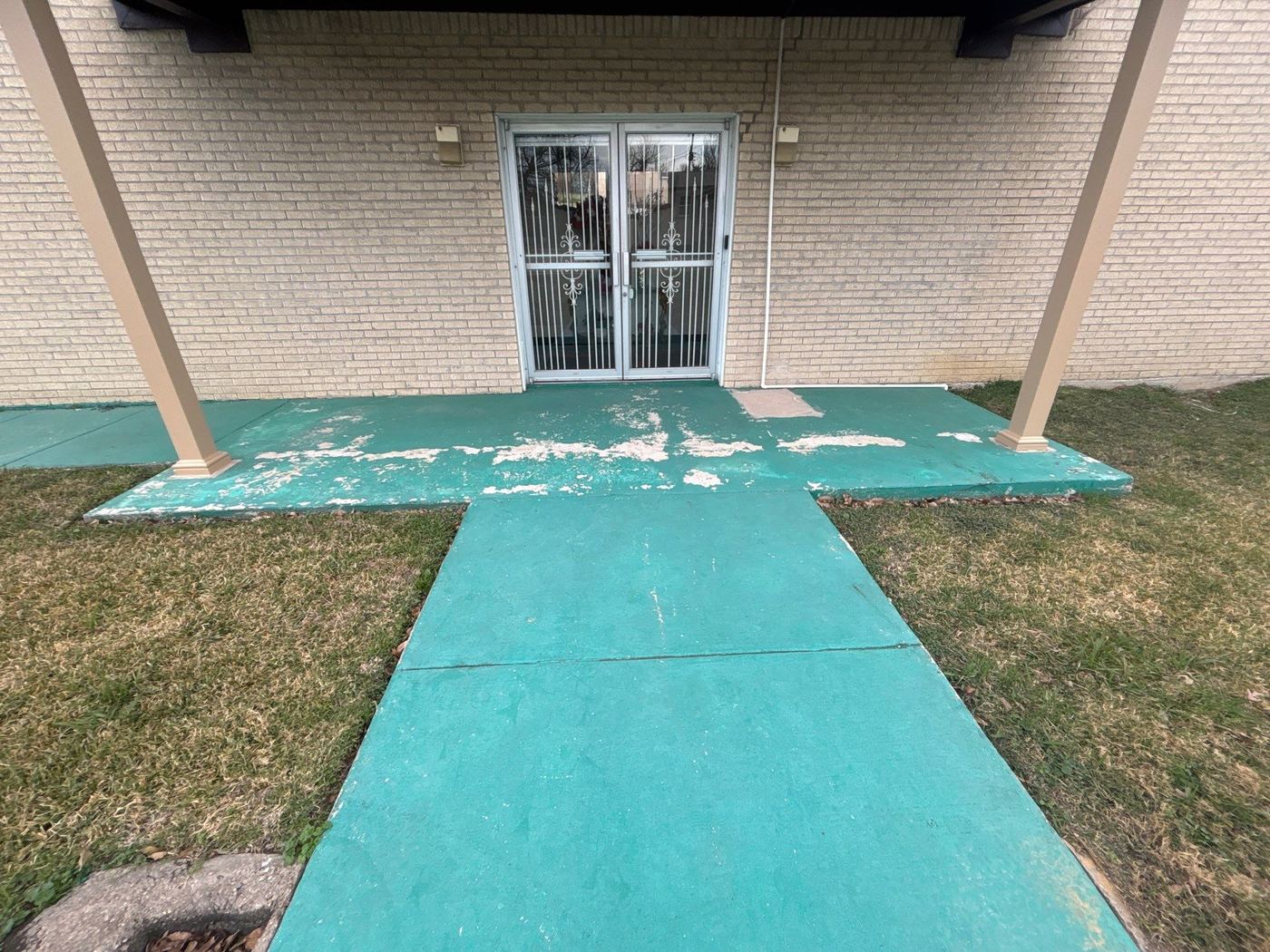 Before: commercial entrance with heavily peeling teal paint — ready for Penntek polyurea resurfacing